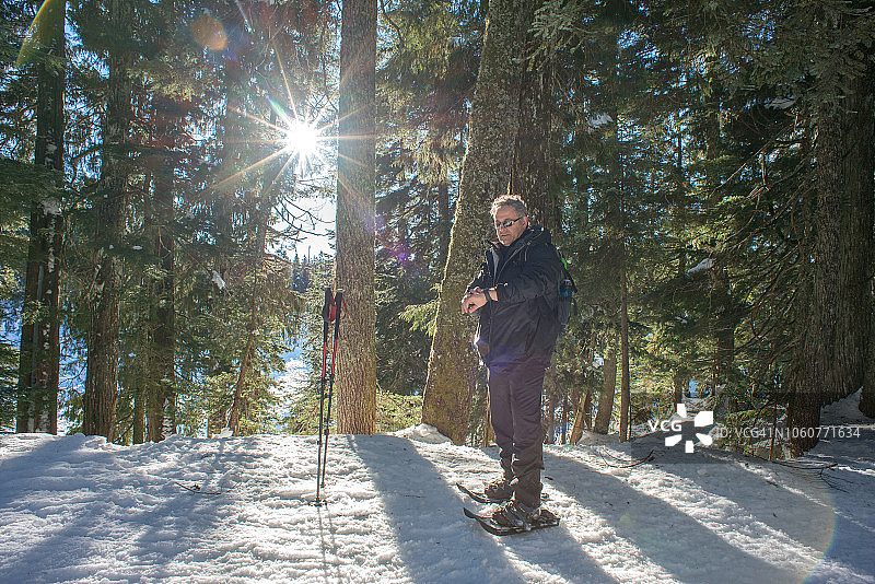 穿着雪鞋的年长男人查看智能手表上的导航应用图片素材