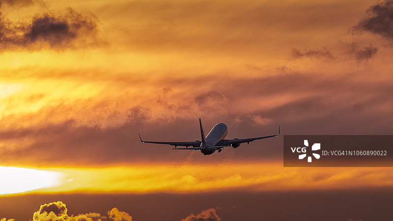 空中飞行的飞机，背景为日落图片素材