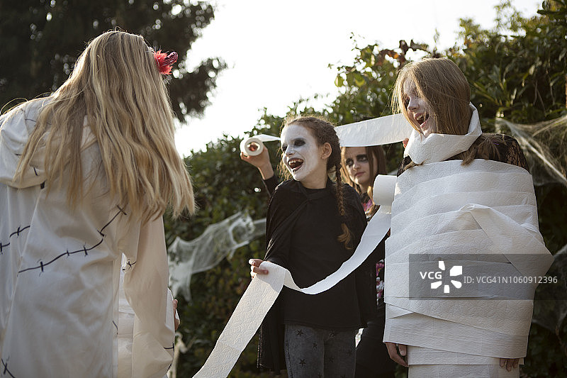 一群年龄较大的孩子玩“木乃伊”万圣节游戏图片素材
