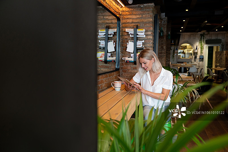 在咖啡馆在线工作的快乐女人图片素材