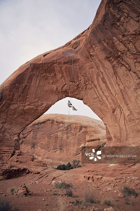 犹他州摩押：攀岩者悬挂在天然拱门下图片素材