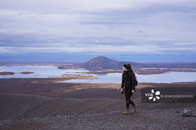 年轻女子走在Hverfjall火山口的山脊上，背景是米湖图片素材