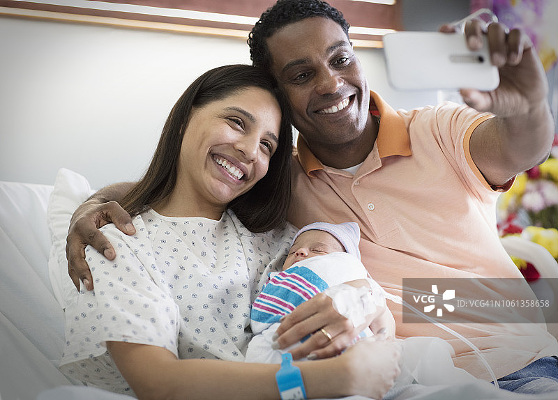 年轻快乐的父母在医院与新生儿自拍图片素材