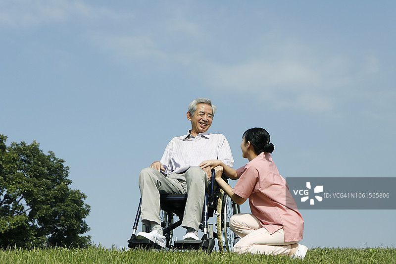 护士帮助坐在轮椅上的老年男人图片素材