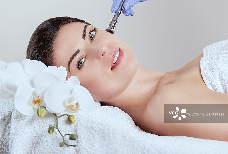 美容师在美容院为年轻女子做面部微晶磨皮图片素材