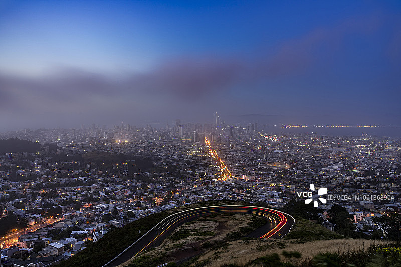 从双子峰观看日落时多云的旧金山天际线图片素材
