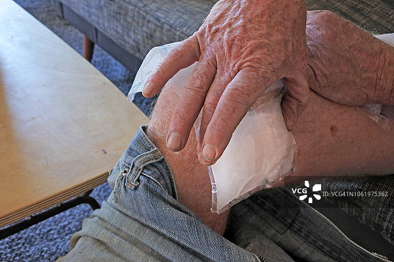 男人在家中发生事故后在受伤的腿上敷冰袋图片素材