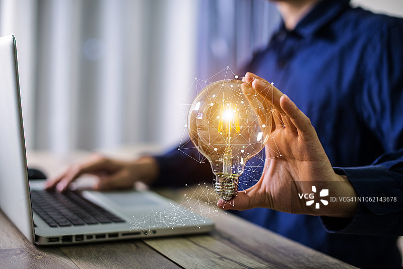 商人手持灯泡，寓意创新技术和创造力图片素材