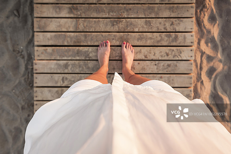 站在沙滩栈桥上向下看的白衬衫女人图片素材