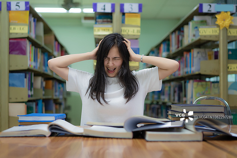 亚洲女学生在大学图书馆里无聊地读书图片素材