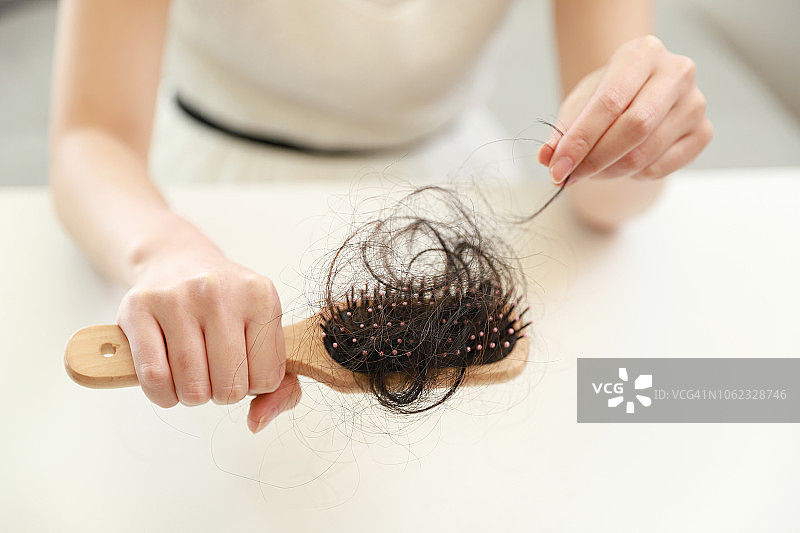 女人拿着带有掉发的发刷图片素材