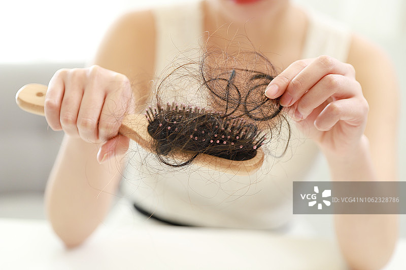 女子手持沾满掉发的梳子特写图片素材