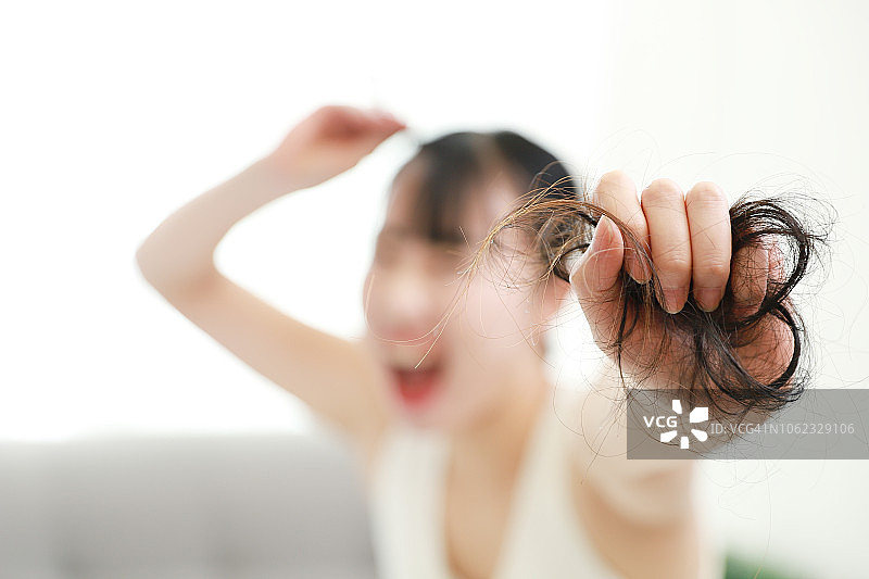 震惊的女士看着掉落的头发图片素材