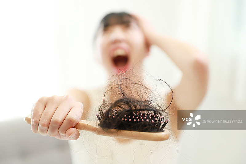 震惊的女人拿着掉发的发刷图片素材