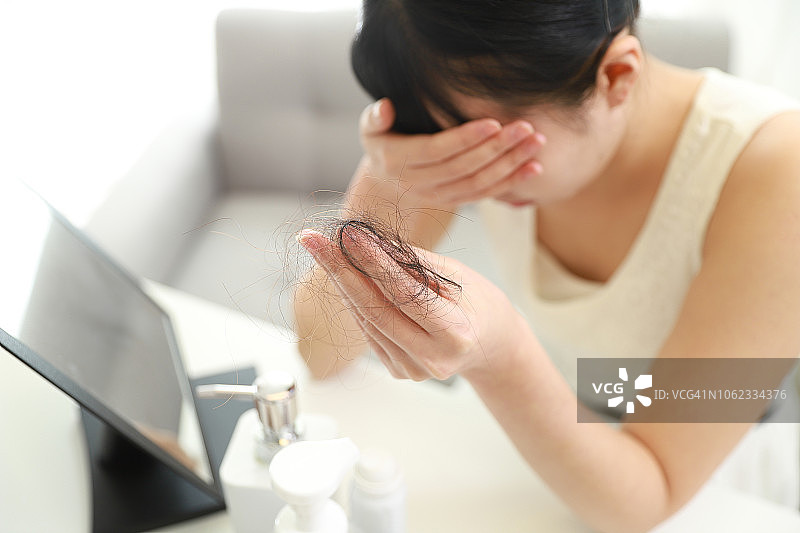 焦虑的女人拿着掉落的头发图片素材
