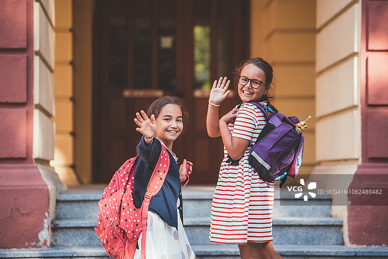 小学生进入教学楼前向父母挥手图片素材