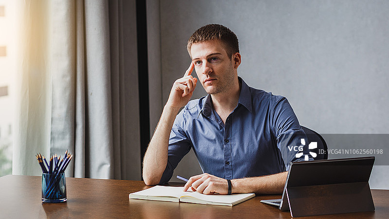 在办公桌前处理文件并眺望城市景色的年轻商人图片素材