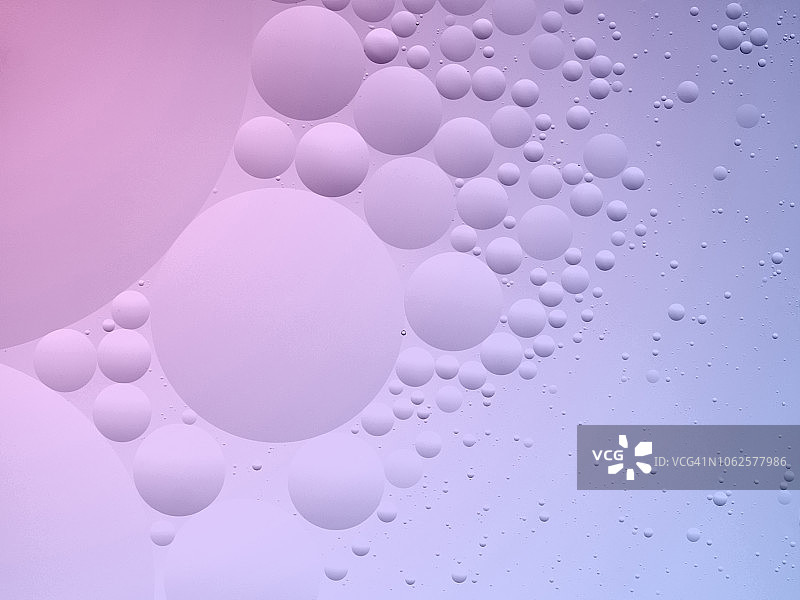 粉紫色液体背景中气泡和水滴形成的抽象形状和纹理全景图片素材