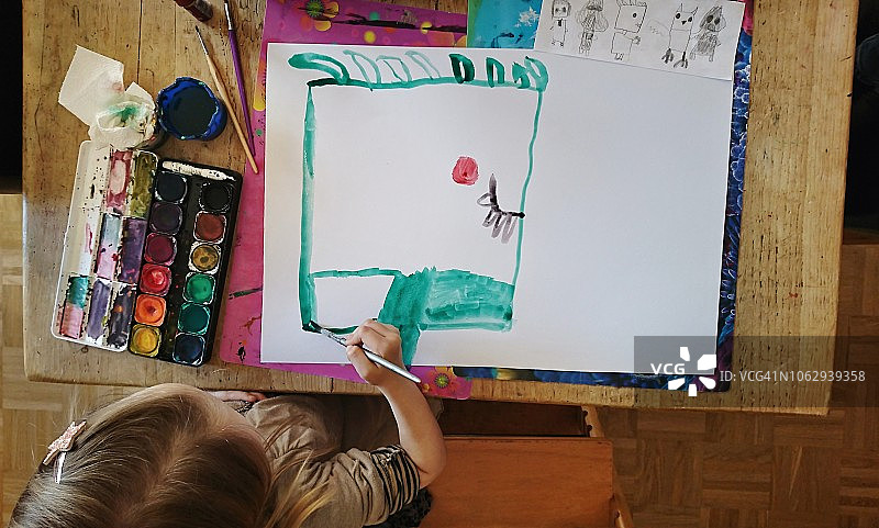 在桌旁画绿色脸谱的孩子图片素材