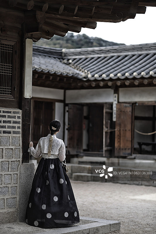身穿韩服的女子在传统韩国房屋后的背影图片素材