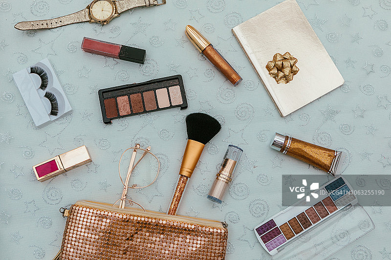金色背景上的女士时尚手提包和化妆刷（顶视图扁平排版，可用于杂志和社交媒体）图片素材