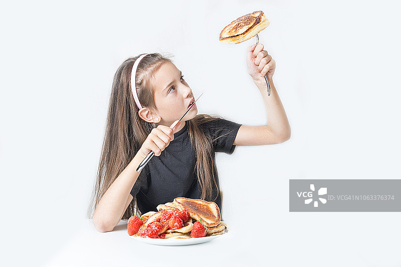 餐桌旁拿着刀叉和煎饼的女孩图片素材