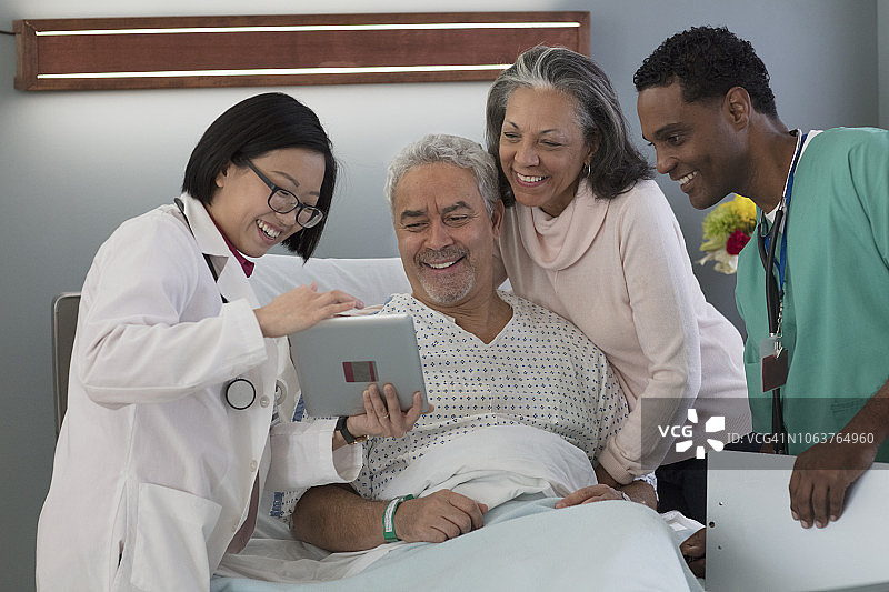 亚洲医生使用平板电脑向老年男子展示检查结果图片素材