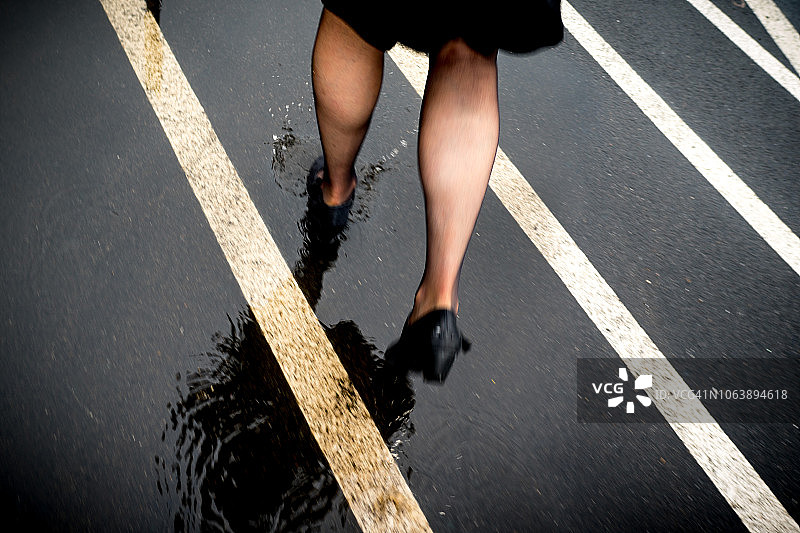 一位穿着高跟鞋、小腿健壮的女人在雨中行走图片素材