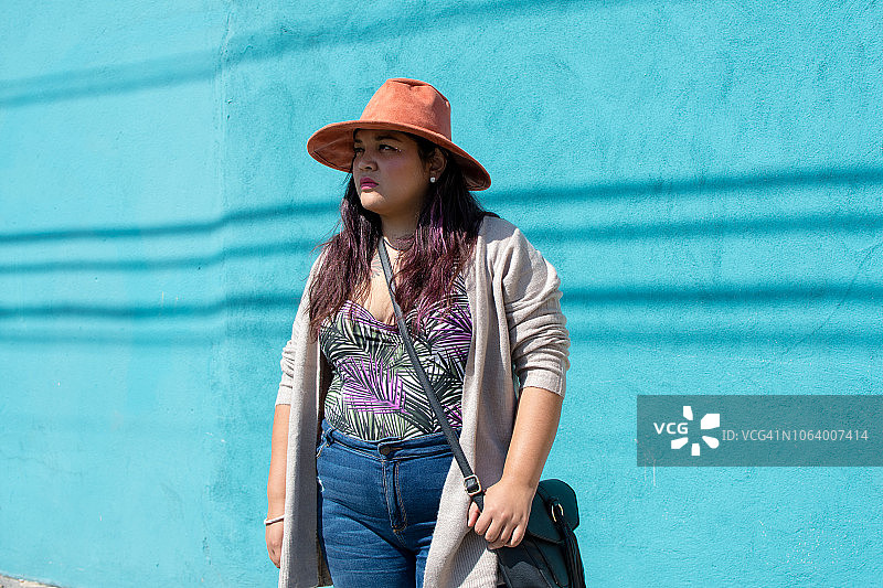 站在蓝色墙前的漂亮拉丁裔女人肖像图片素材