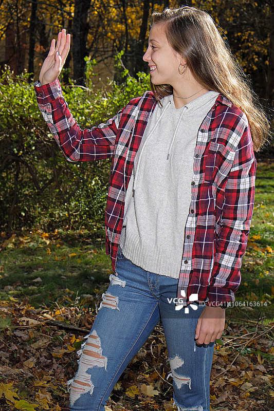 挥舞着秋叶背景的16岁女孩图片素材