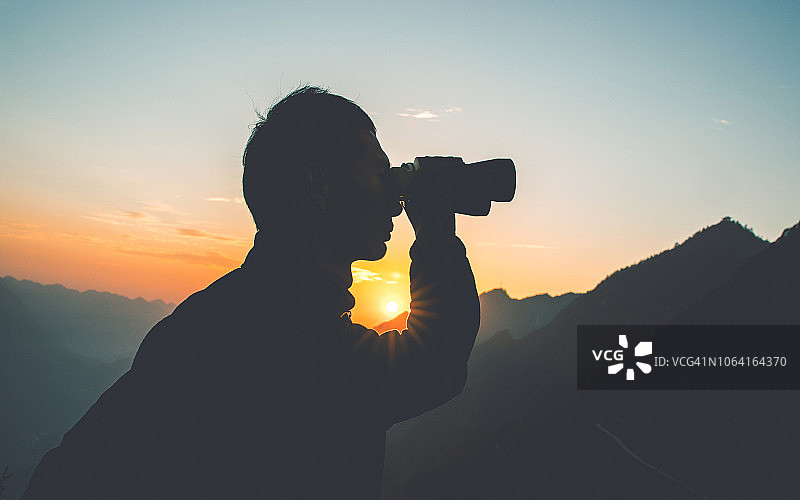 男人在山中用双筒望远镜观察图片素材
