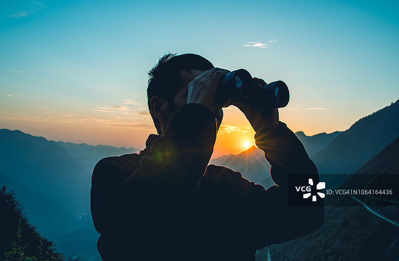 男人在山中用双筒望远镜观察图片素材