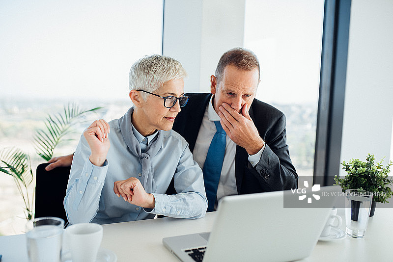 使用笔记本电脑的老年同事图片素材