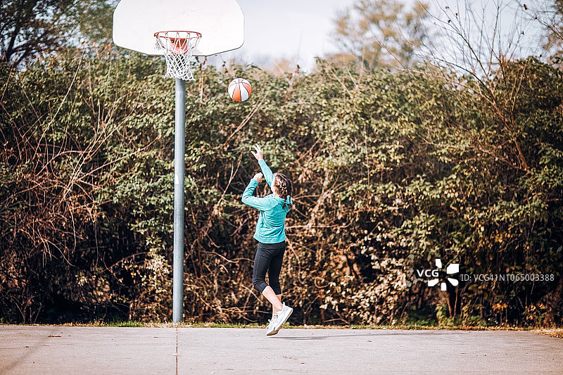 青少年女孩在室外篮球场投篮图片素材