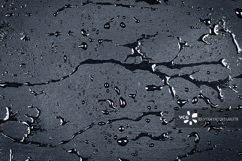 玄武岩或花岗岩深色石材表面的水滴图片素材