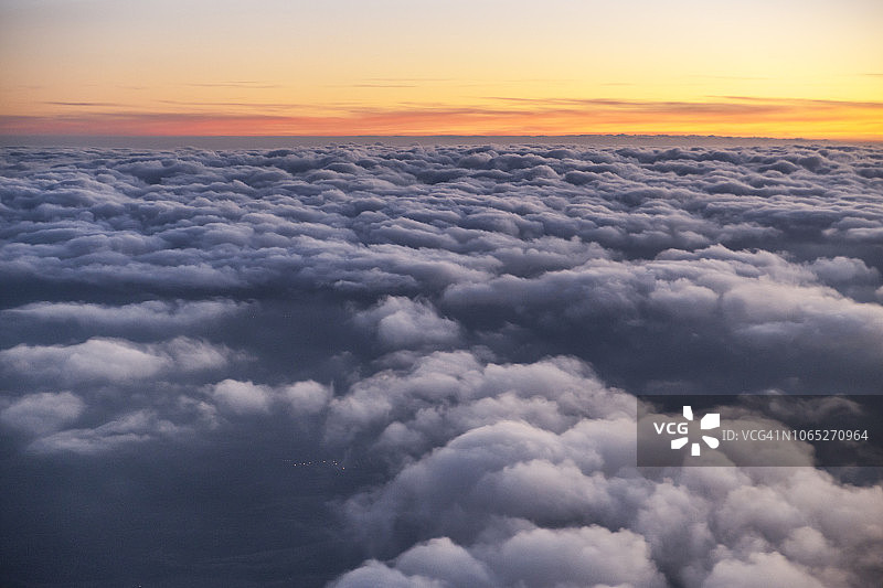 在日落时飞越云层。从飞机舷窗看到的景色图片素材