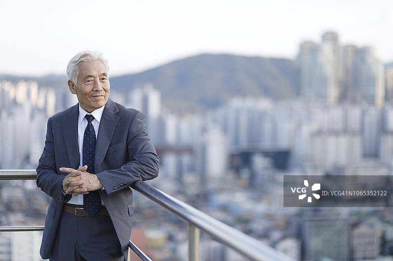 年长的商人站在阳台栏杆上图片素材