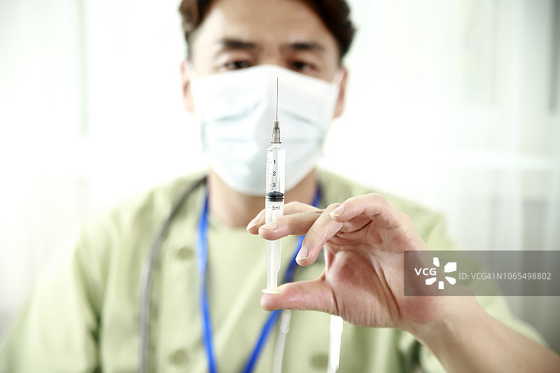 拿着注射器的中年医生图片素材
