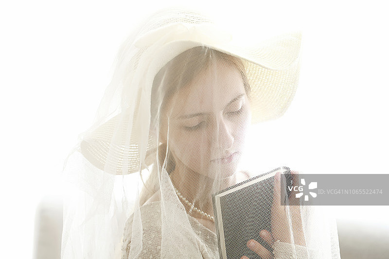 戴着白色面纱的女人拿着书图片素材