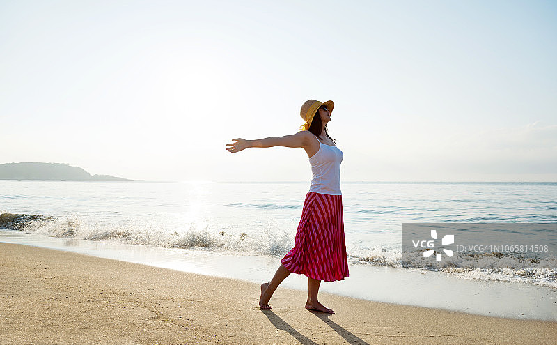 年轻女人在海滩上张开双臂图片素材