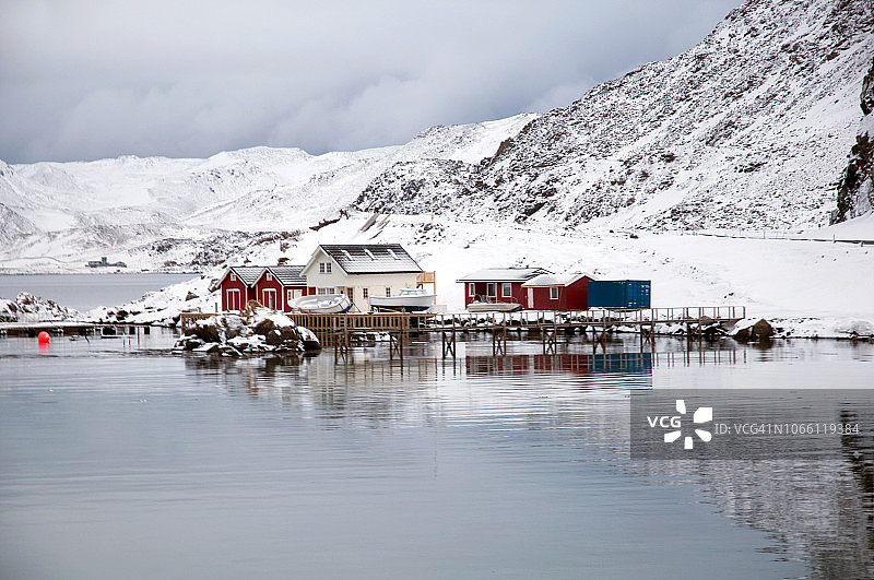 挪威北部北角附近的水域海湾和红色木制传统高脚屋图片素材