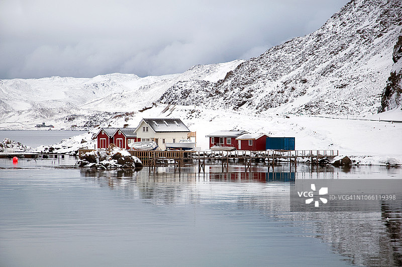 挪威北部北角附近的水域海湾和红色木制传统高脚屋图片素材