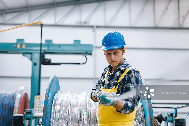 在工厂使用电缆盘工作的年轻商务男士肖像图片素材