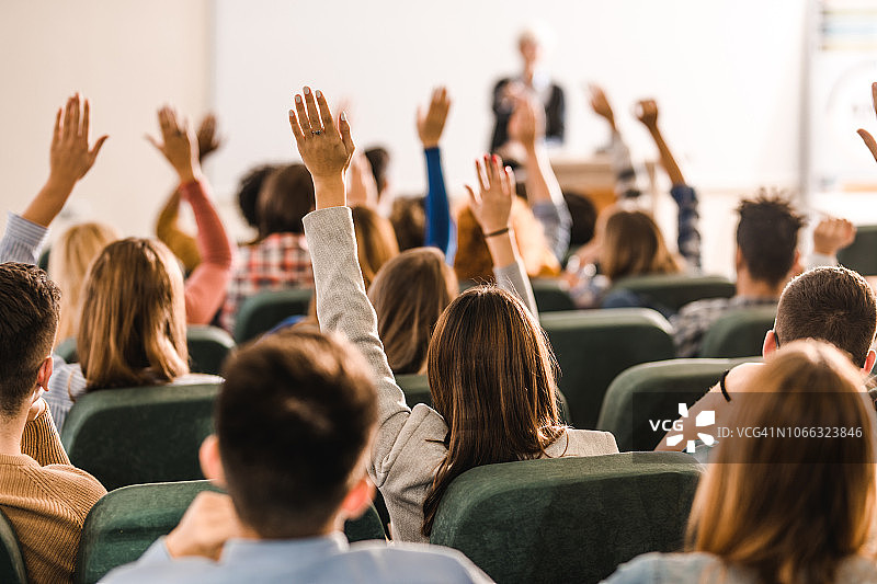 圆形剧场上课时，一大群举手的学生的背影图片素材