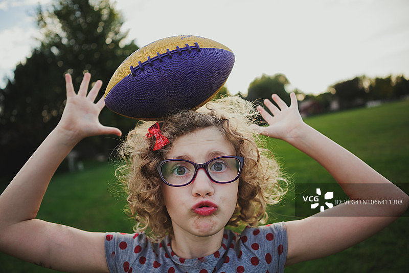 女孩头顶平衡着一个橄榄球图片素材