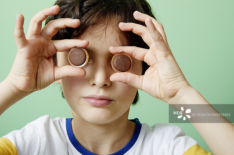 小男孩拿着巧克力太妃糖放在眼前图片素材