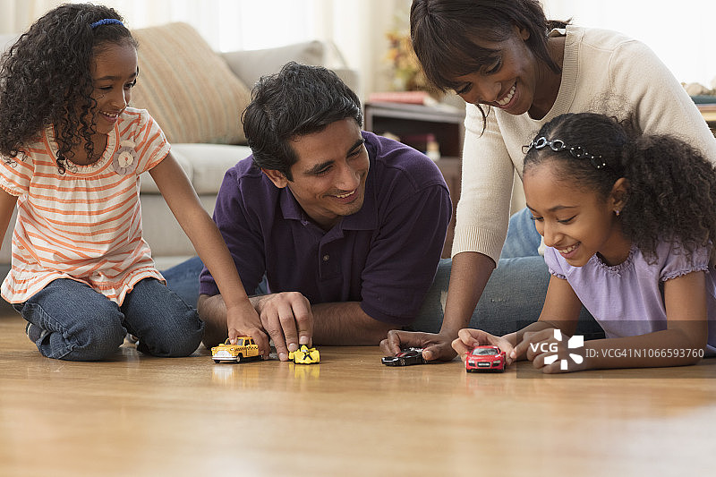 多民族家庭在地板上玩玩具车图片素材
