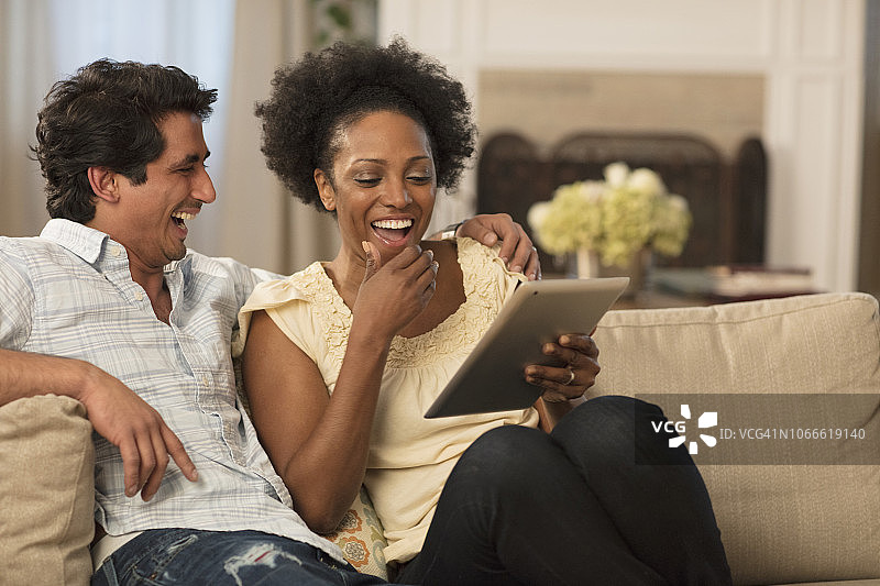 年轻夫妇在客厅沙发上使用平板电脑放松图片素材