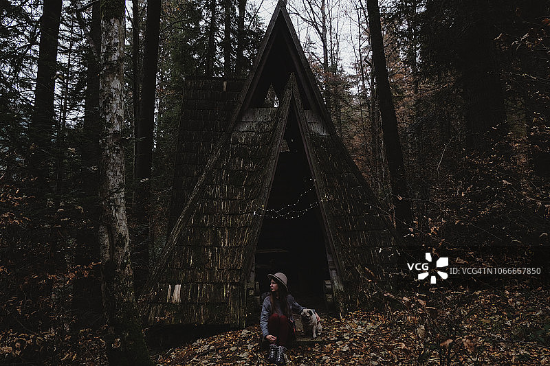 戴帽子的女人和狗用圣诞灯装饰山区废弃的木屋图片素材