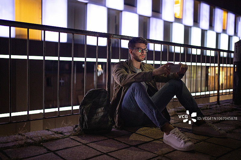 坐在屋顶上玩手机的现代潮人图片素材